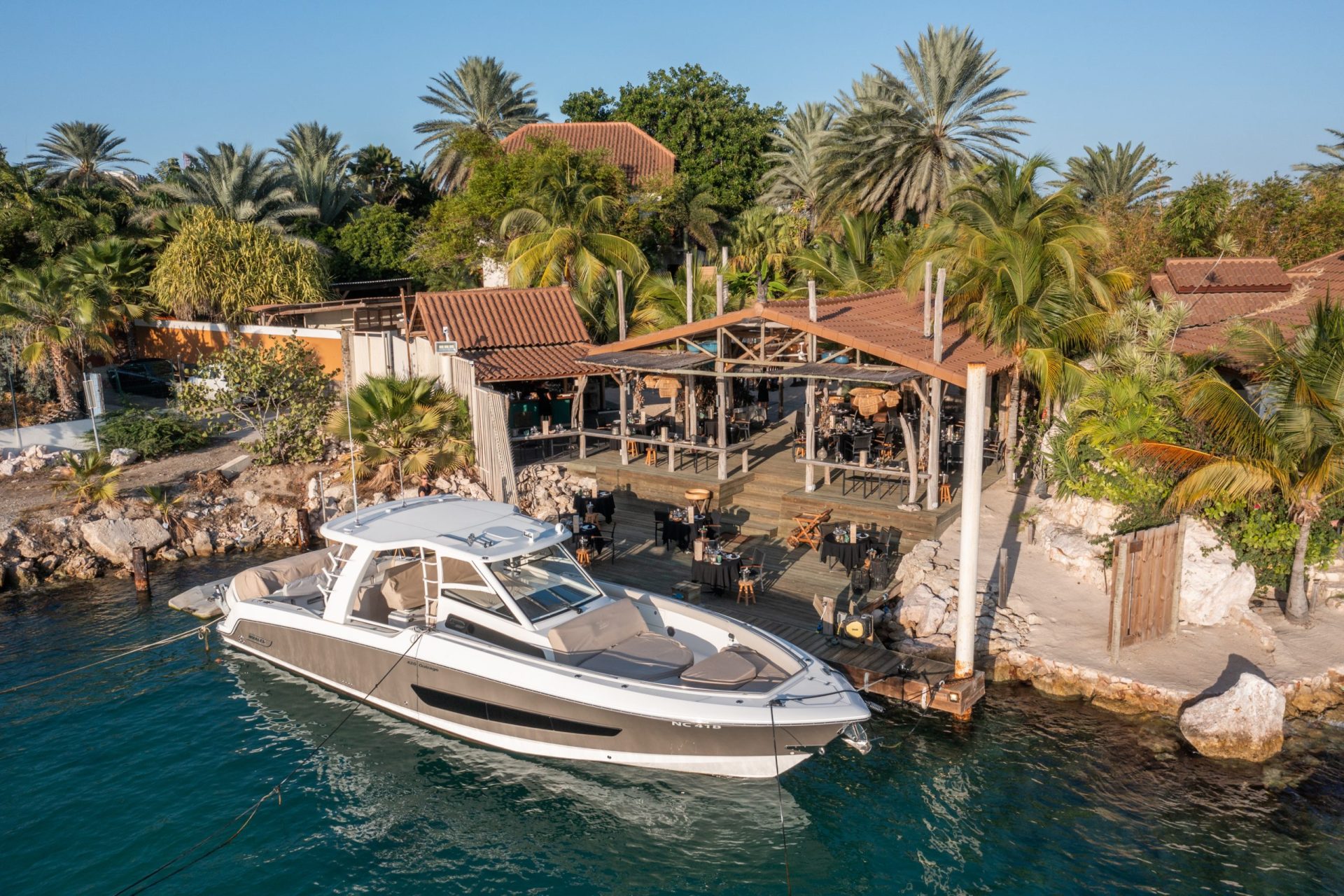 Aerial view of a yacht docked at a jetty next to a restaurant