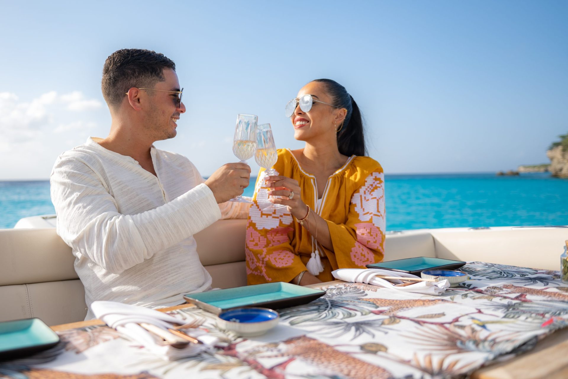 A man and a woman cheering with champagne glasses on a yacht