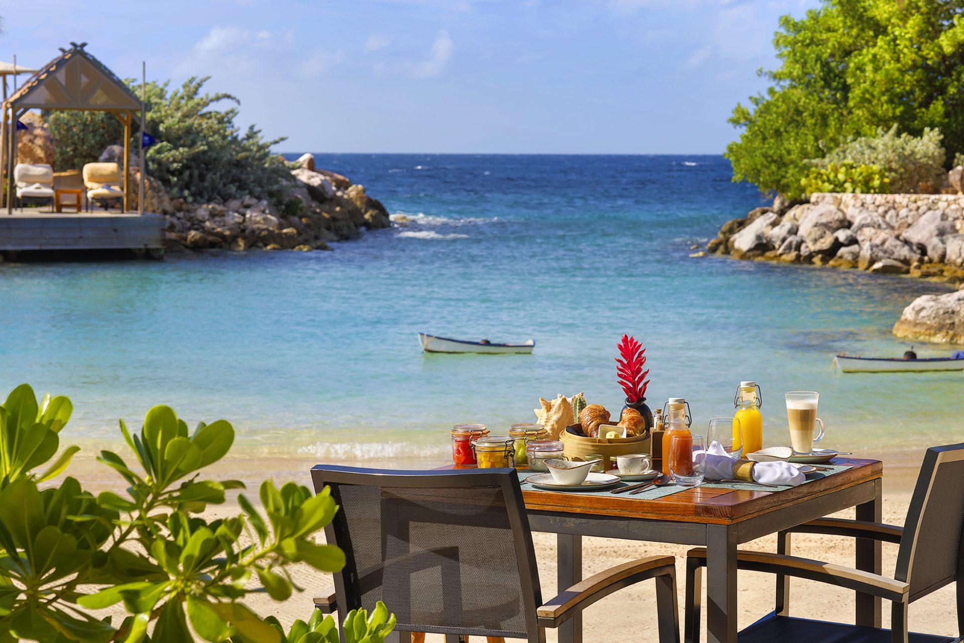 A table set-up for breakfast on the beach with the sea in the background