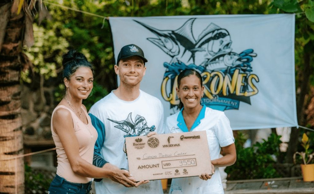 Three people holding a gift check of 9550USD for the Curacao medical center