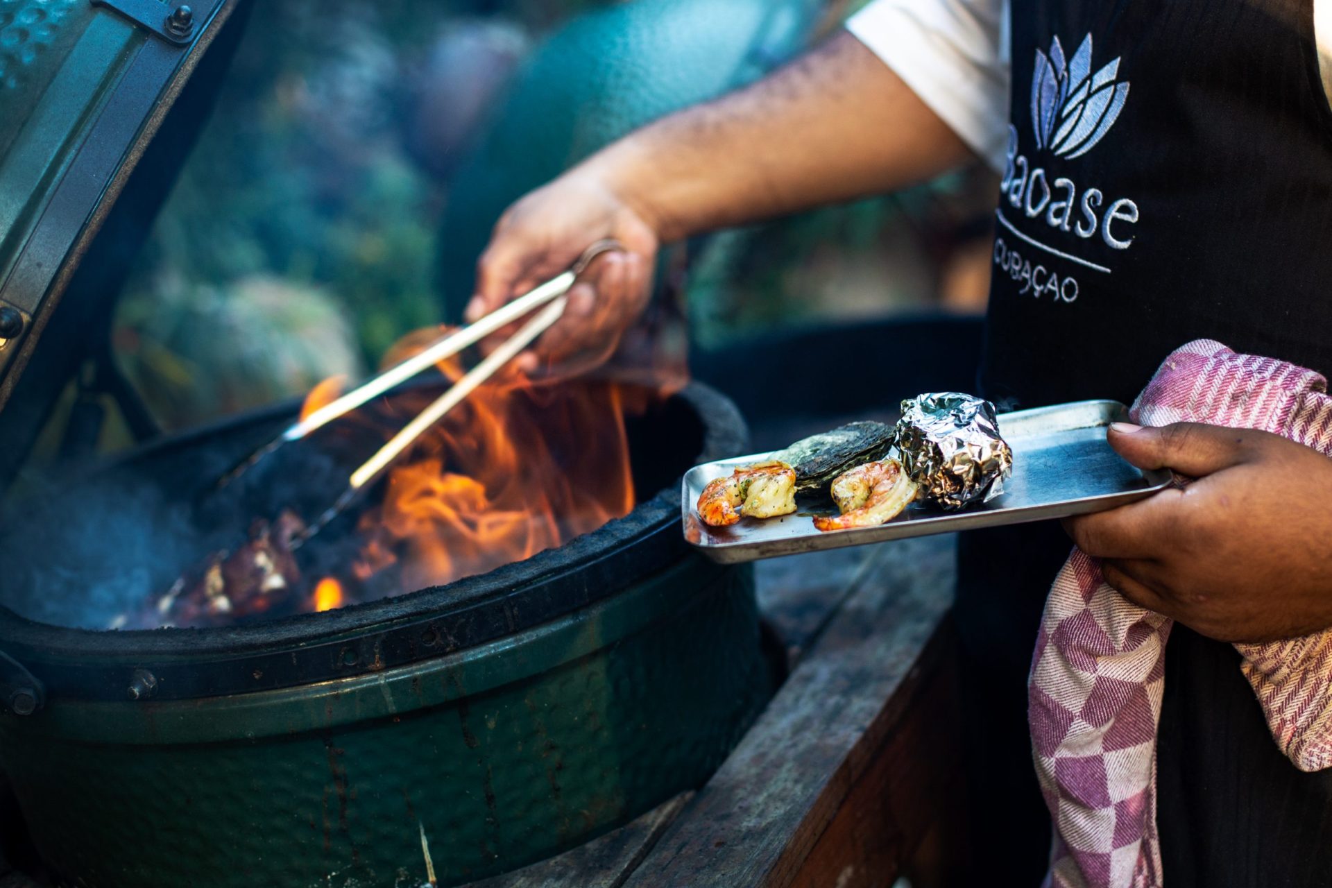 Close-up of a Baoase chef taking food of the barbecue and on a plate