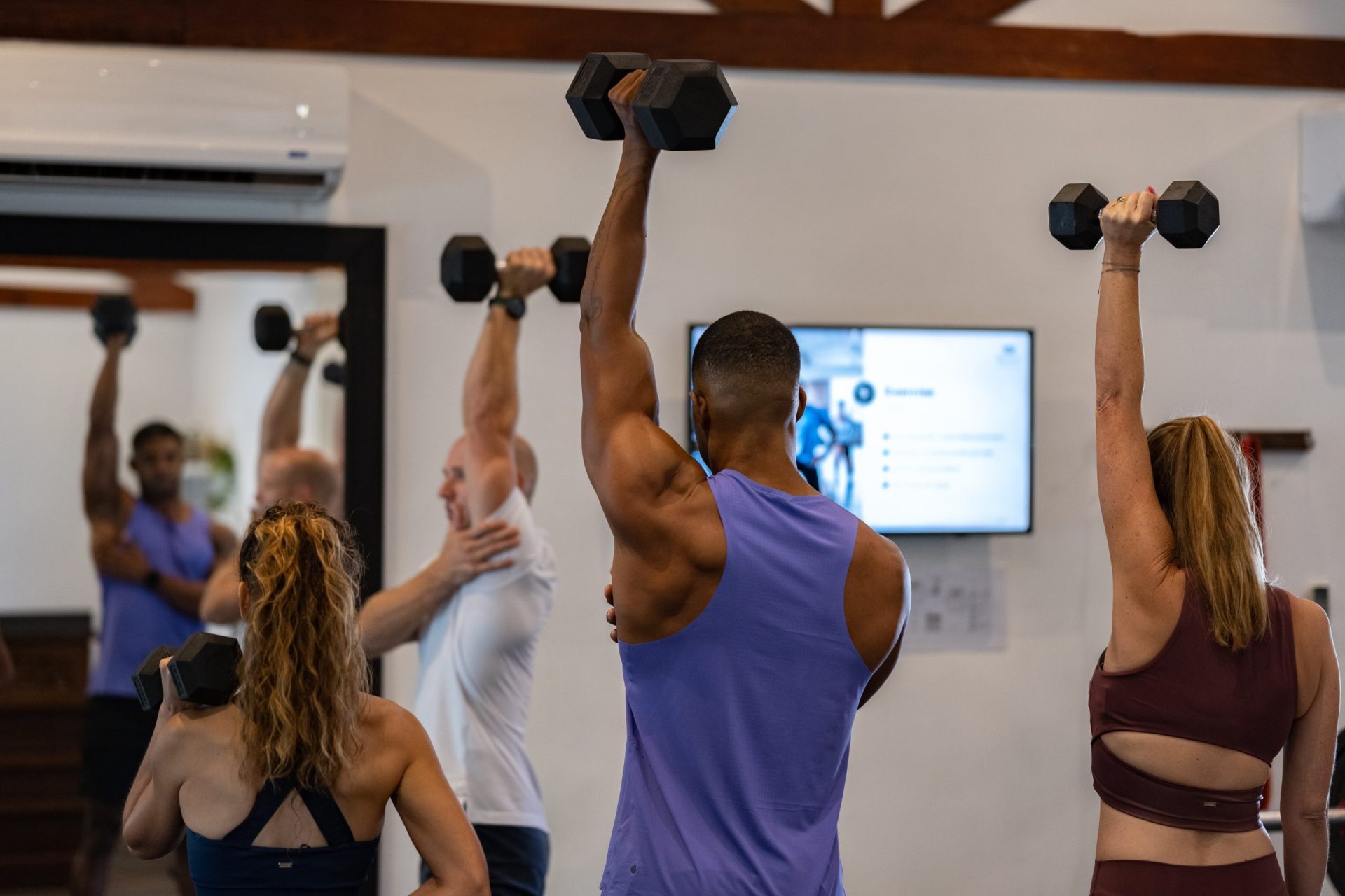 A man training another man and 2 women in a work out
