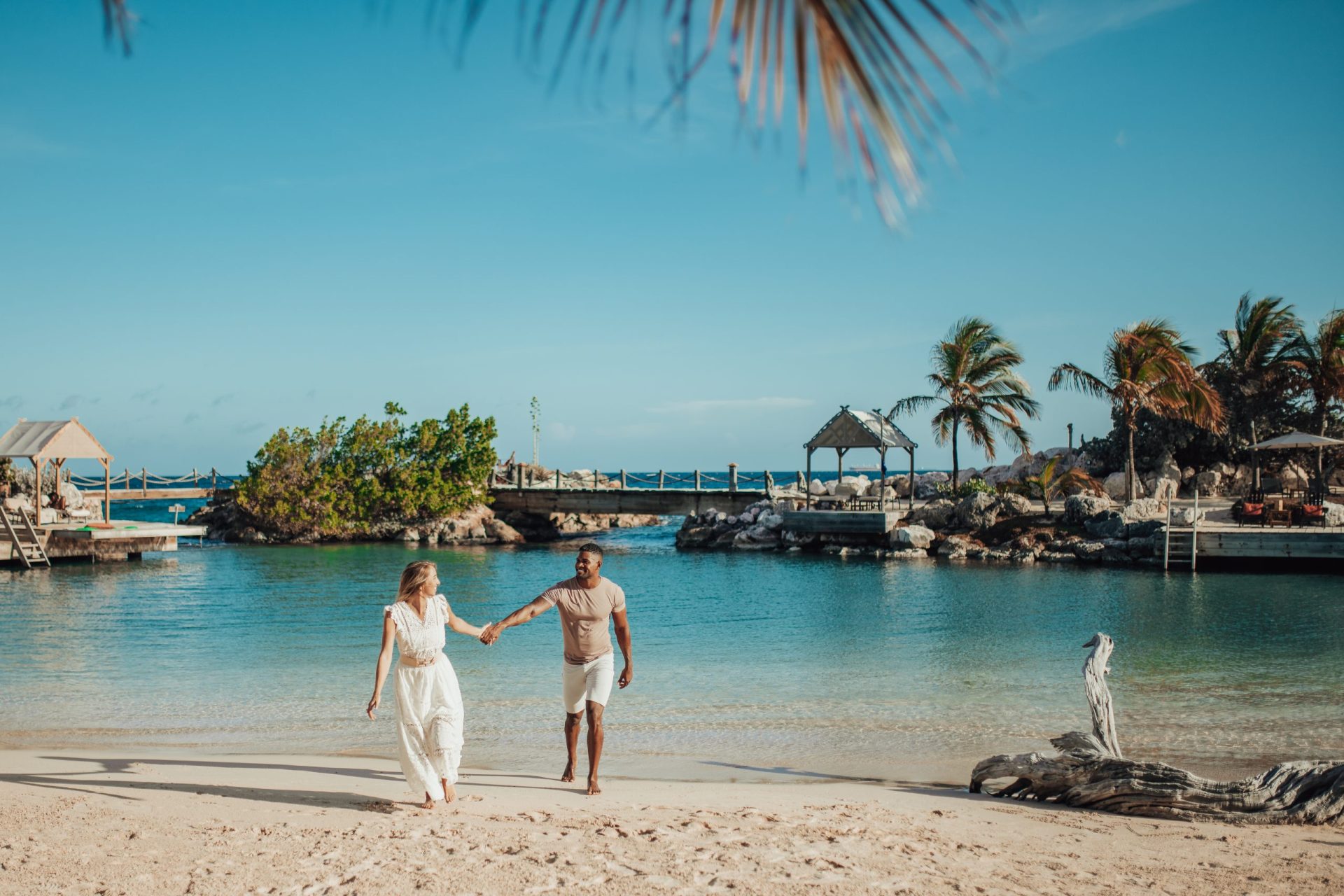 Man and woman on the beach at Baoase, walking away from the water while holding hands